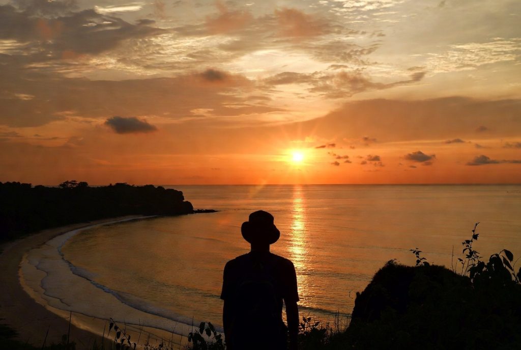 Siluet seorang traveler menatap matahari terbenam di ufuk Samudera Hindia dari pesisir Aceh